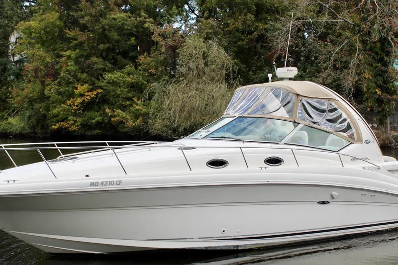 The Image of 2004 Sea Ray 340 Sundancer boat cruising on a calm river with lush greenery. - 1