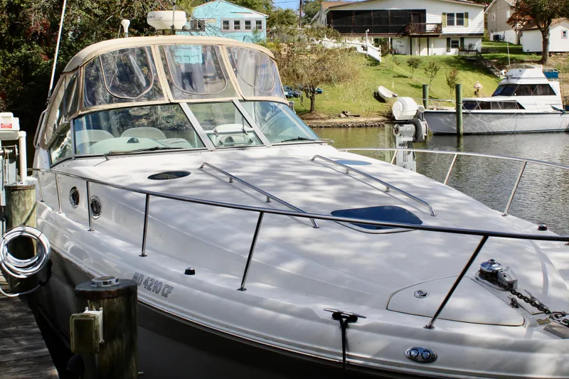 Slide: The Image of 2004 Sea Ray 340 Sundancer docked by a scenic waterfront with houses in the background. - 13
