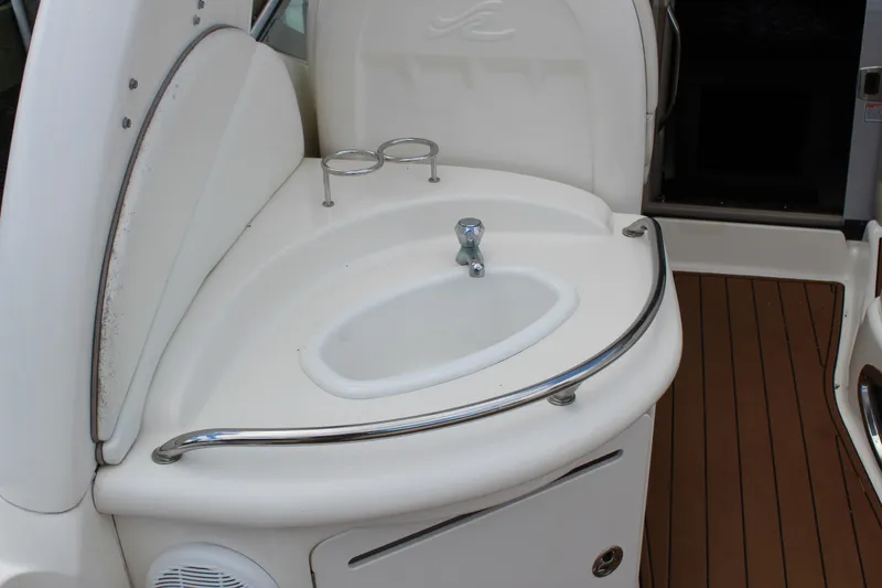 Slide: The Image of 2004 Sea Ray 340 Sundancer boat sink area with cup holders and wooden flooring. - 16