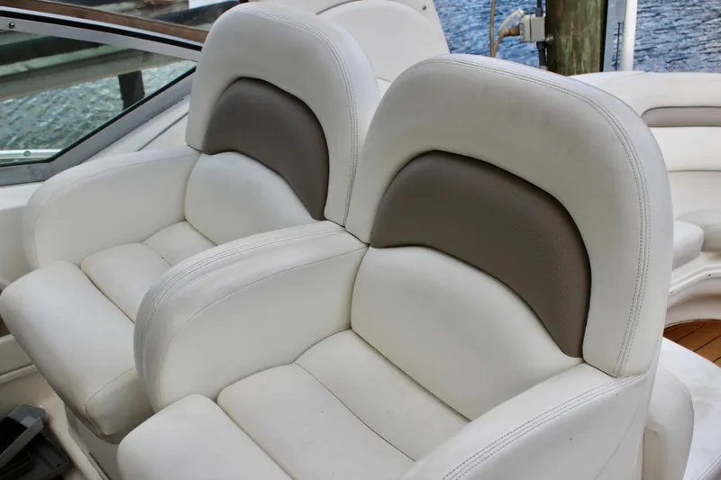 Slide: The Image of 2004 Sea Ray 340 Sundancer boat seats, white and gray, near water. - 20