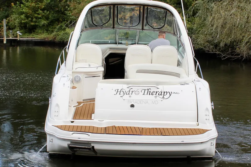Slide: The Image of 2004 Sea Ray 340 Sundancer boat named "Hydro Therapy" on calm water, rear view. - 5