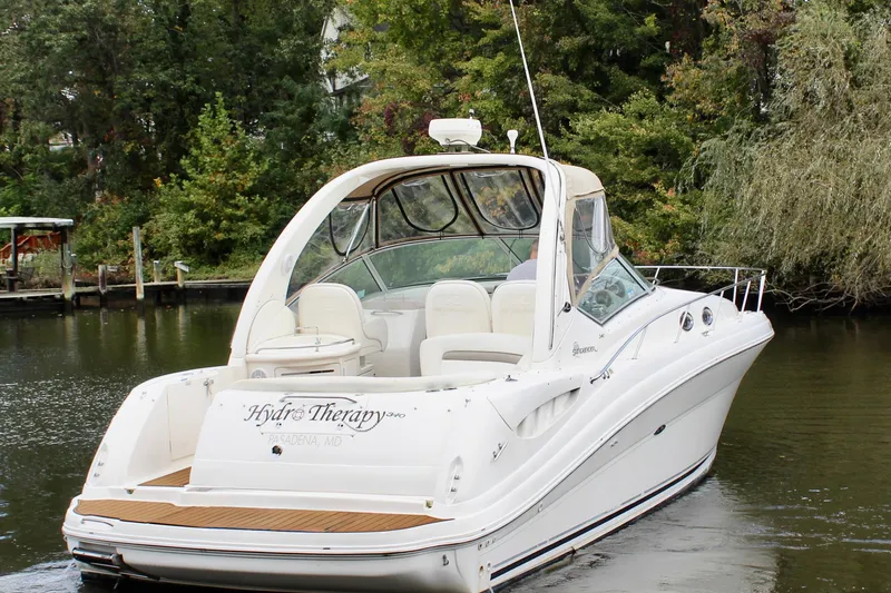 Slide: The Image of 2004 Sea Ray 340 Sundancer boat on a calm river, surrounded by lush greenery. - 6