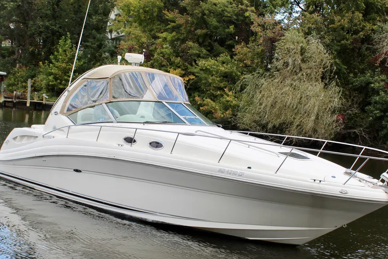 Slide: The Image of 2004 Sea Ray 340 Sundancer boat on a calm river, surrounded by lush greenery. - 9