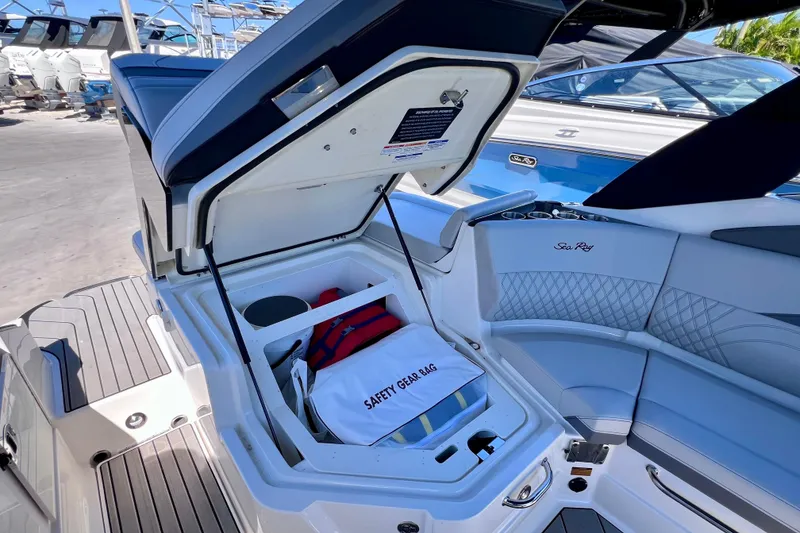 Slide: The Image of 2024 Sea Ray SLX 260 Outboard boat with open storage compartment and safety gear bag. - 28