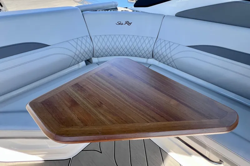 Slide: The Image of 2024 Sea Ray SLX 260 Outboard interior with wooden table and cushioned seating. - 63