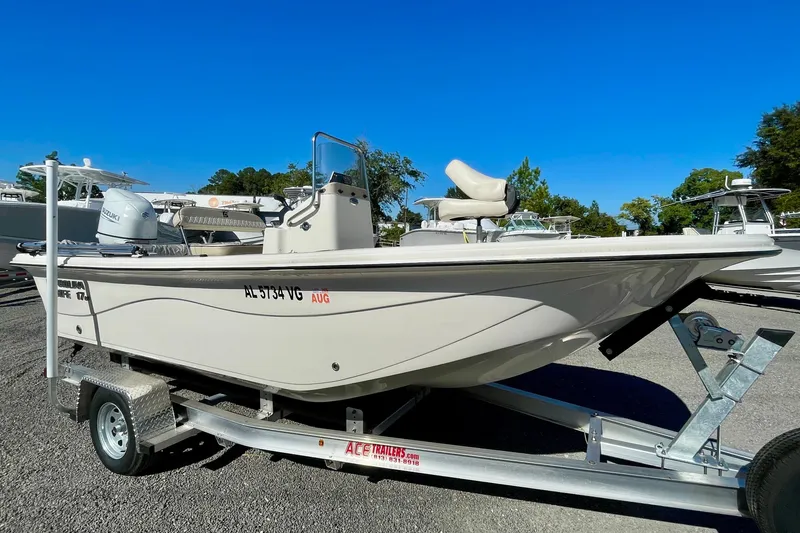 The Image of 2021 Carolina Skiff 17 LS boat on trailer, parked outdoors under clear blue sky. - 0