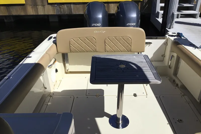 Slide: The Image of 2016 Chris-Craft Calypso 26 boat interior with table and dual engines. - 13