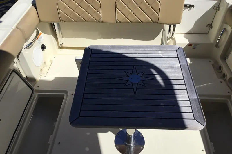 Slide: The Image of 2016 Chris-Craft Calypso 26 interior with cushioned seating and wooden table. - 19