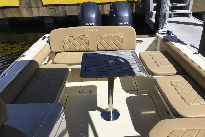 Slide: The Image of 2016 Chris-Craft Calypso 26 boat interior with beige seating and a central table. - 26