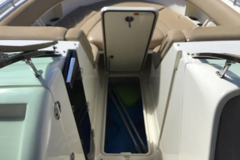 Slide: The Image of 2016 Chris-Craft Calypso 26 interior with open storage compartments and beige seating. - 32