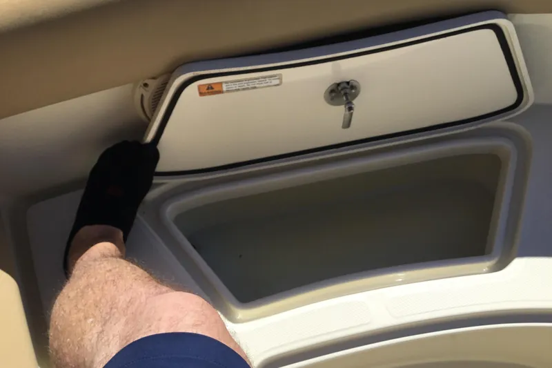 Slide: The Image of 2016 Chris-Craft Calypso 26 storage compartment with a person's leg and foot visible. - 37