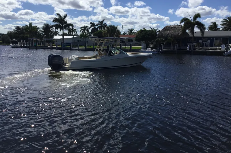 Slide: The Image of 2016 Chris-Craft Calypso 26 boat cruising on a sunny, palm-lined waterway. - 48