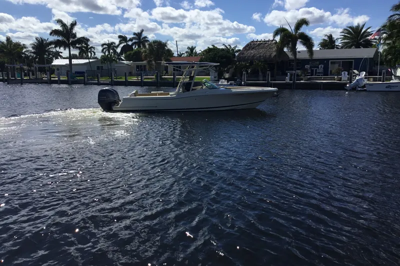 Slide: The Image of 2016 Chris-Craft Calypso 26 boat cruising on a sunny waterfront with palm trees. - 49