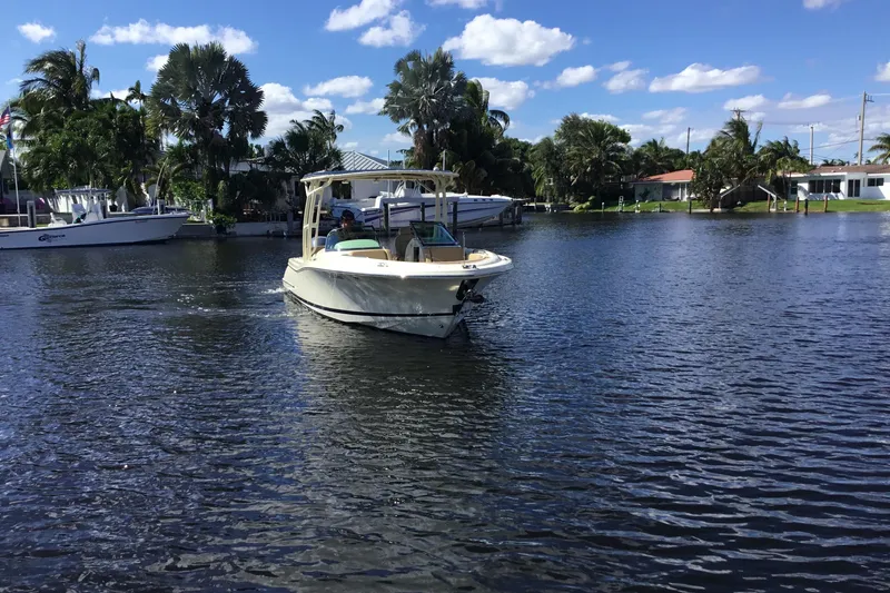 Slide: The Image of 2016 Chris-Craft Calypso 26 boat cruising on a sunny, palm-lined waterway. - 52