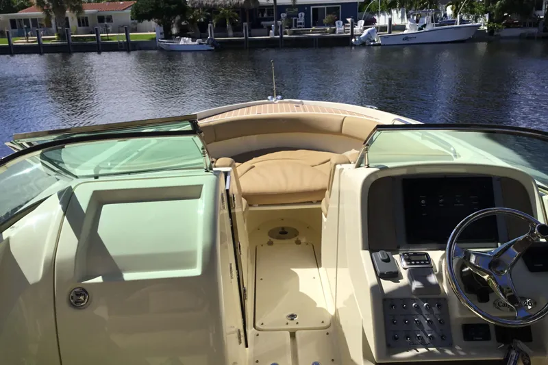Slide: The Image of 2016 Chris-Craft Calypso 26 boat interior with helm and seating, docked by waterfront homes. - 6