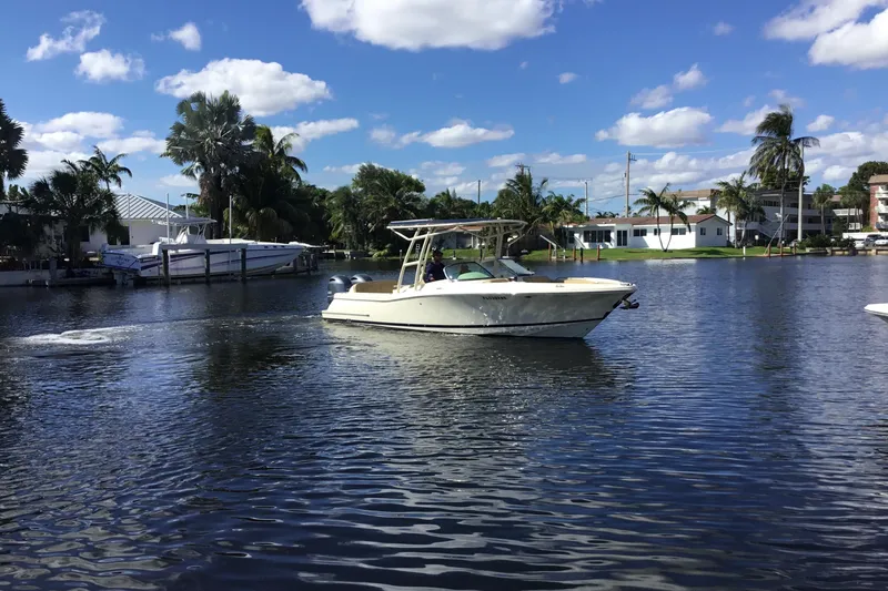 Slide: The Image of 2016 Chris-Craft Calypso 26 boat cruising on a sunny, palm-lined waterway. - 60