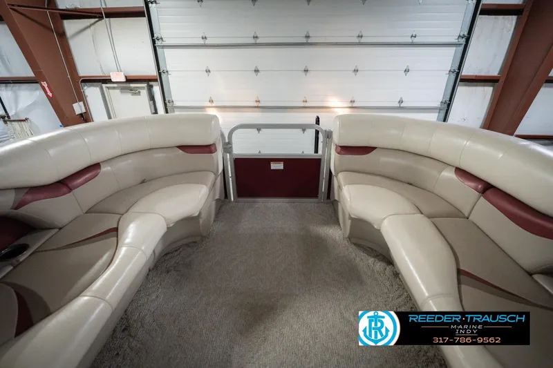 Slide: The Image of 2010 Sylvan 8522 Mirage Cruise interior with beige and maroon seating in a garage. - 21
