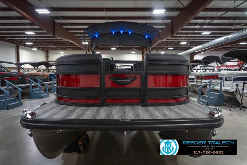 Slide: The Image of 2026 Bennington 25 RSB pontoon boat in showroom, rear view with red and black design. - 5