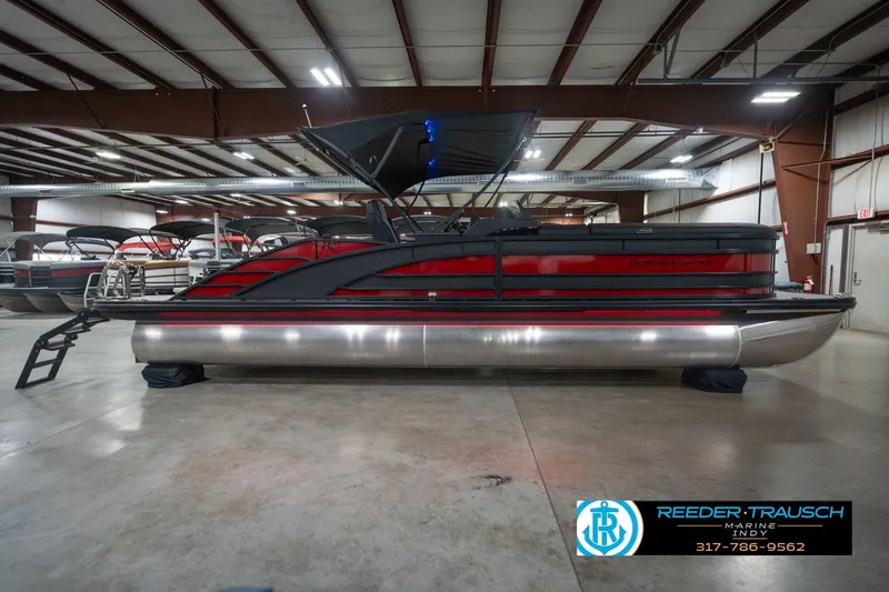 Slide: The Image of 2026 Bennington 25 RSB pontoon boat in showroom, featuring sleek red and black design. - 7
