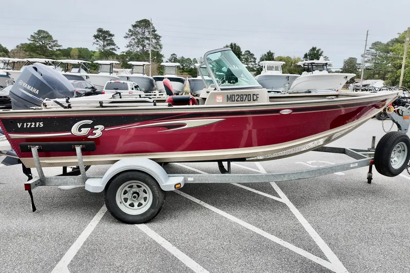 Slide: The Image of 2013 G3 Angler V172 F boat on trailer, red and beige, parked in a lot. - 3