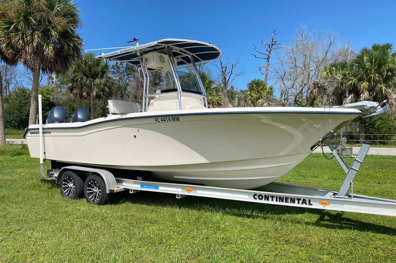 Slide: The Image of 2005 Grady-White Advance 257 boat on trailer, parked on grass with palm trees. - 1