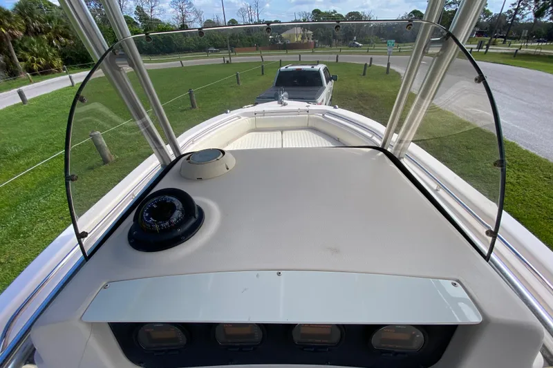 Slide: The Image of 2005 Grady-White Advance 257 boat dashboard with compass and windshield, parked on grass. - 62