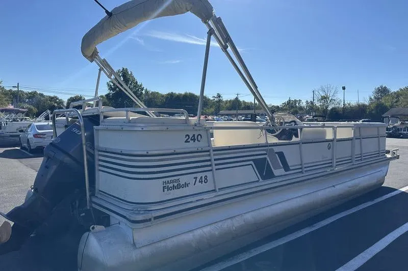 Slide: The Image of 1997 Harris 240 pontoon boat parked in a lot under clear blue sky. - 3