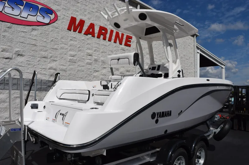 Slide: The Image of 2026 Yamaha Boats 222 FSH Sport E displayed at dealership, sleek design under blue sky. - 4