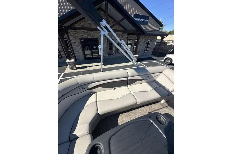 Slide: The Image of 2019 Bennington 22 SSRCX boat interior with beige seating, parked outside MasterCraft building. - 16