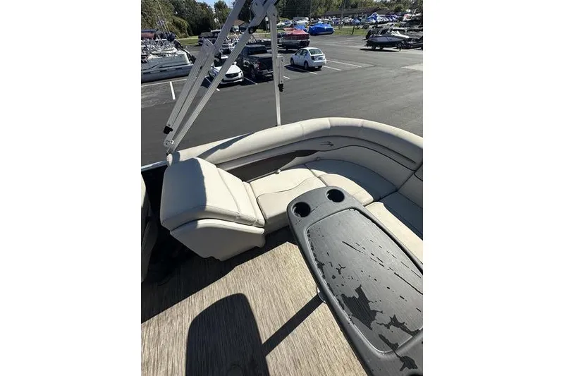 Slide: The Image of 2019 Bennington 22 SSRCX boat interior with beige seating and table, parked in a lot. - 18