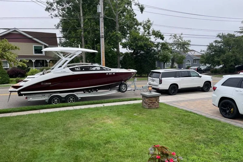 The Image of 2021 Yamaha Boats 275SD on trailer, parked in suburban neighborhood driveway. - 1