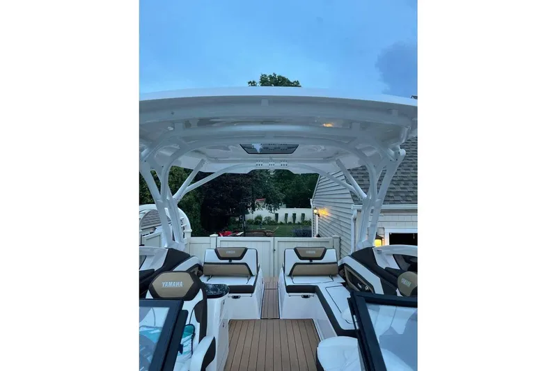 Slide: The Image of 2021 Yamaha Boats 275SD interior with seating and canopy, docked near a house. - 9