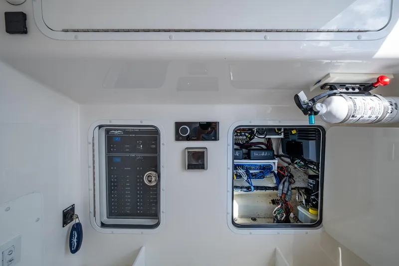 Slide: The Image of 2023 Invincible 36 Open Fisherman control panel and wiring compartment with fire extinguisher. - 30
