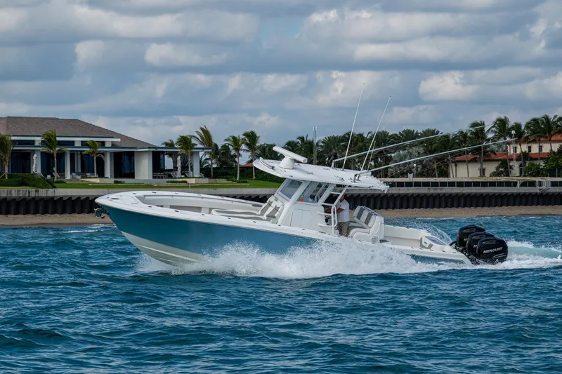 Slide: The Image of 2023 Invincible 36 Open Fisherman boat cruising on blue ocean near luxury waterfront homes. - 33