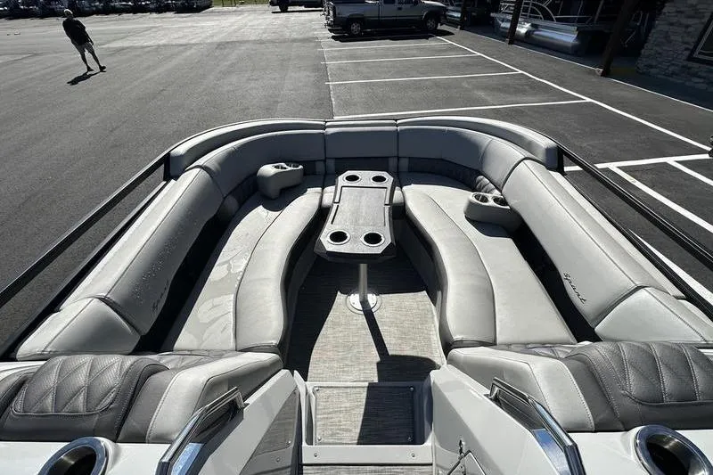 Slide: The Image of 2021 Bennington 24 RTFB pontoon boat with spacious seating and cup holders in a parking lot. - 13