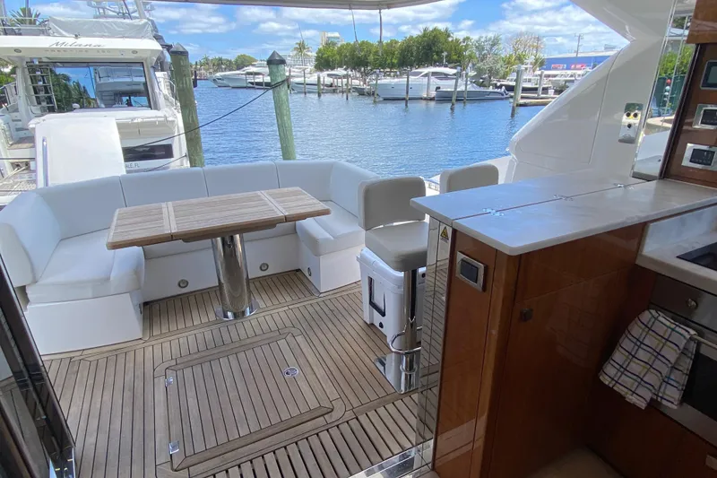 Slide: The Image of Luxurious 2017 Sunseeker Manhattan 52 yacht deck with seating and table, docked at marina. - 17