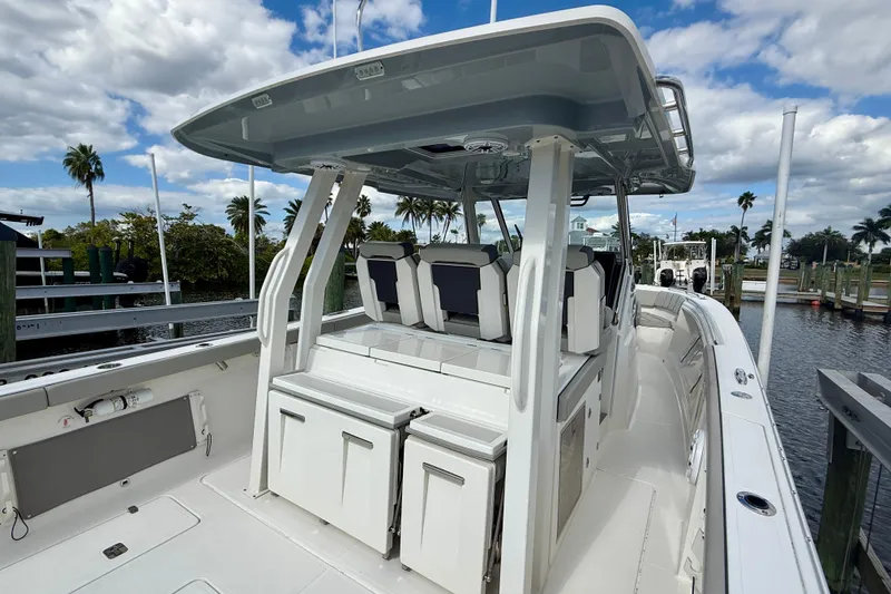 Slide: The Image of 2023 Pursuit S 358 Sport boat interior with seating and storage, docked under a cloudy sky. - 24