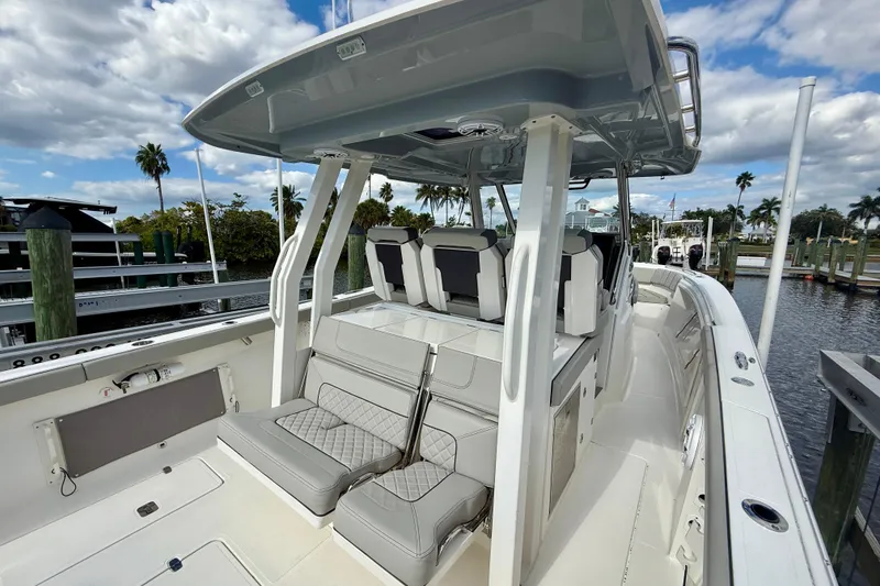 Slide: The Image of 2023 Pursuit S 358 Sport boat interior with seating, docked by palm trees. - 25