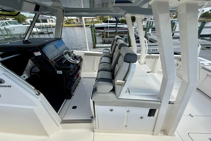 Slide: The Image of 2023 Pursuit S 358 Sport boat interior with helm and seating, docked by the water. - 31