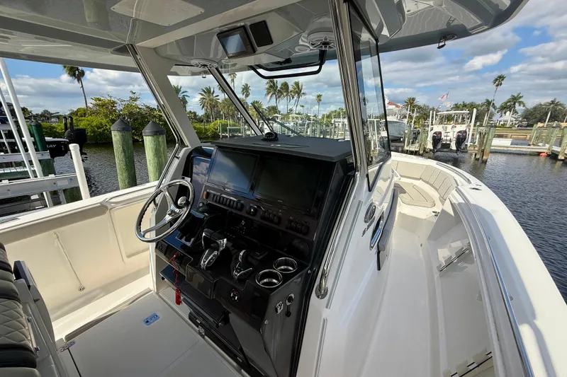 Slide: The Image of 2023 Pursuit S 358 Sport boat interior with modern dashboard and scenic marina view. - 42