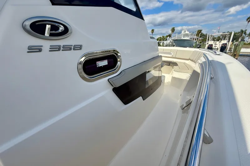Slide: The Image of 2023 Pursuit S 358 Sport boat, sleek design, docked under a partly cloudy sky. - 48