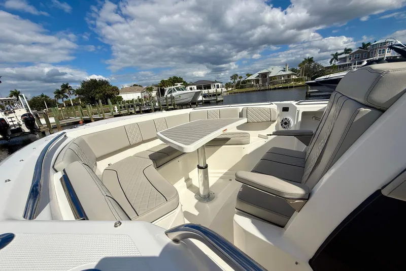 Slide: The Image of 2023 Pursuit S 358 Sport boat interior with luxurious seating and table, dockside view. - 51