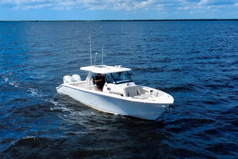 Slide: The Image of 2023 Pursuit S 358 Sport boat cruising on open water under a blue sky. - 6