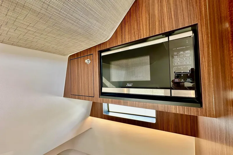 Slide: The Image of 2023 Pursuit S 358 Sport interior with built-in microwave and wood paneling. - 63