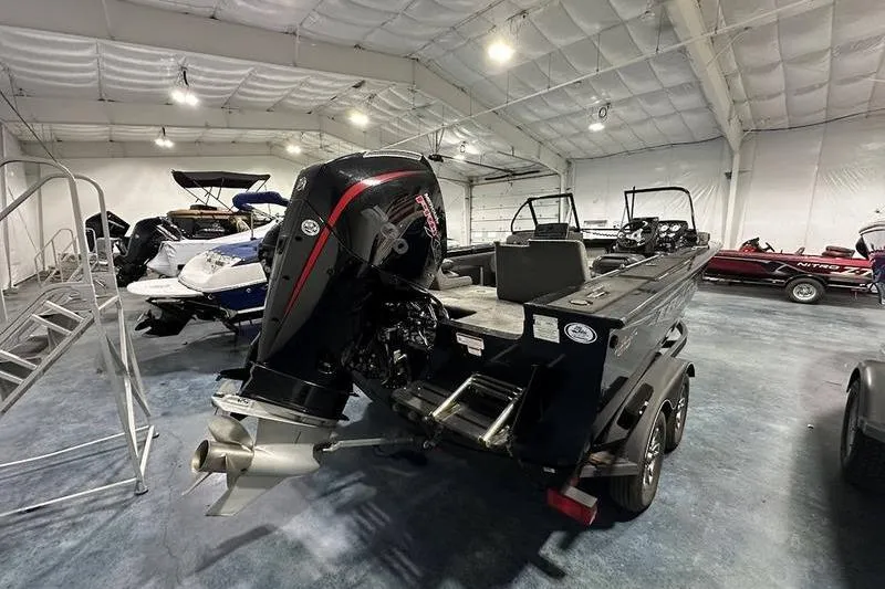 Slide: The Image of 2022 Tracker Targa V-19 Combo boat interior with seating and motor in a showroom. - 2