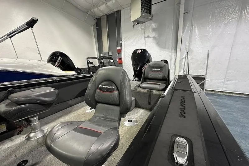Slide: The Image of 2022 Tracker Targa V-19 Combo boat interior with seating and motor in a showroom. - 6