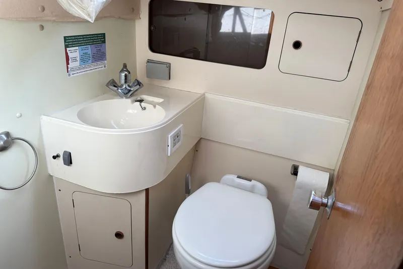 Slide: The Image of Compact bathroom in a 1987 Moody 346 sailboat, featuring a sink and toilet. - 19