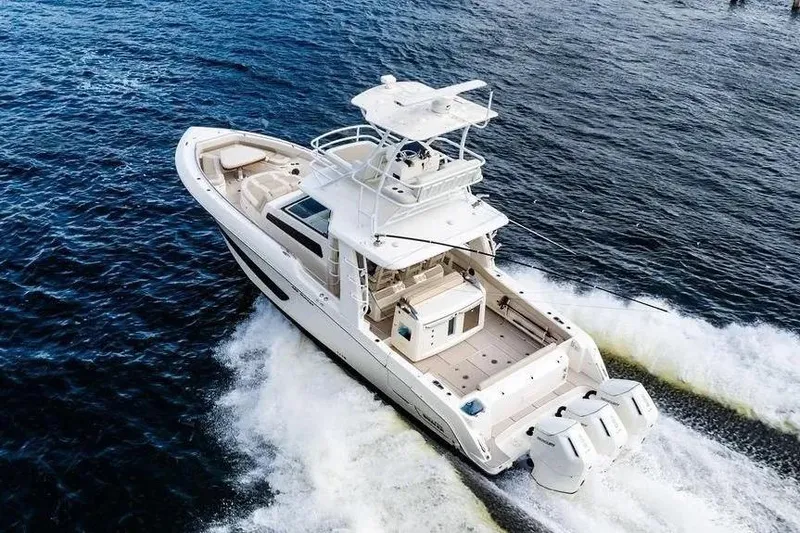 Slide: The Image of 2022 Boston Whaler 420 Outrage cruising on open water, showcasing sleek design and powerful engines. - 11