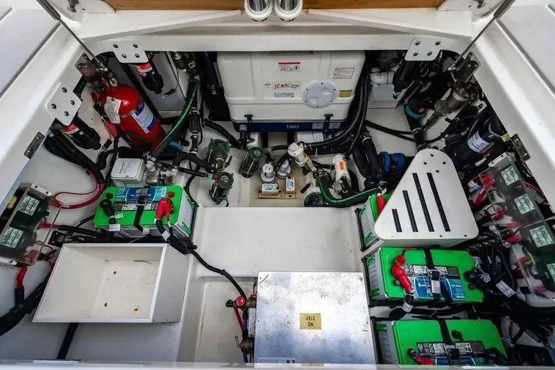 Slide: The Image of Engine compartment of 2022 Boston Whaler 420 Outrage, showcasing batteries and equipment. - 24