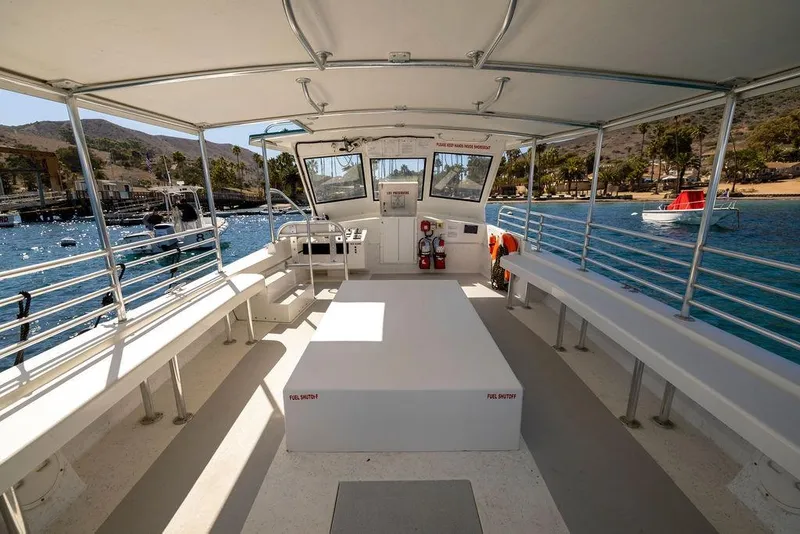 Slide: The Image of 2018 Seahawk Island Hopper boat interior with seating, docked by a scenic waterfront. - 7